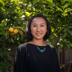 Professor Betty Yu Profile picture black shirt, blue necklace, in front of lemon tree
